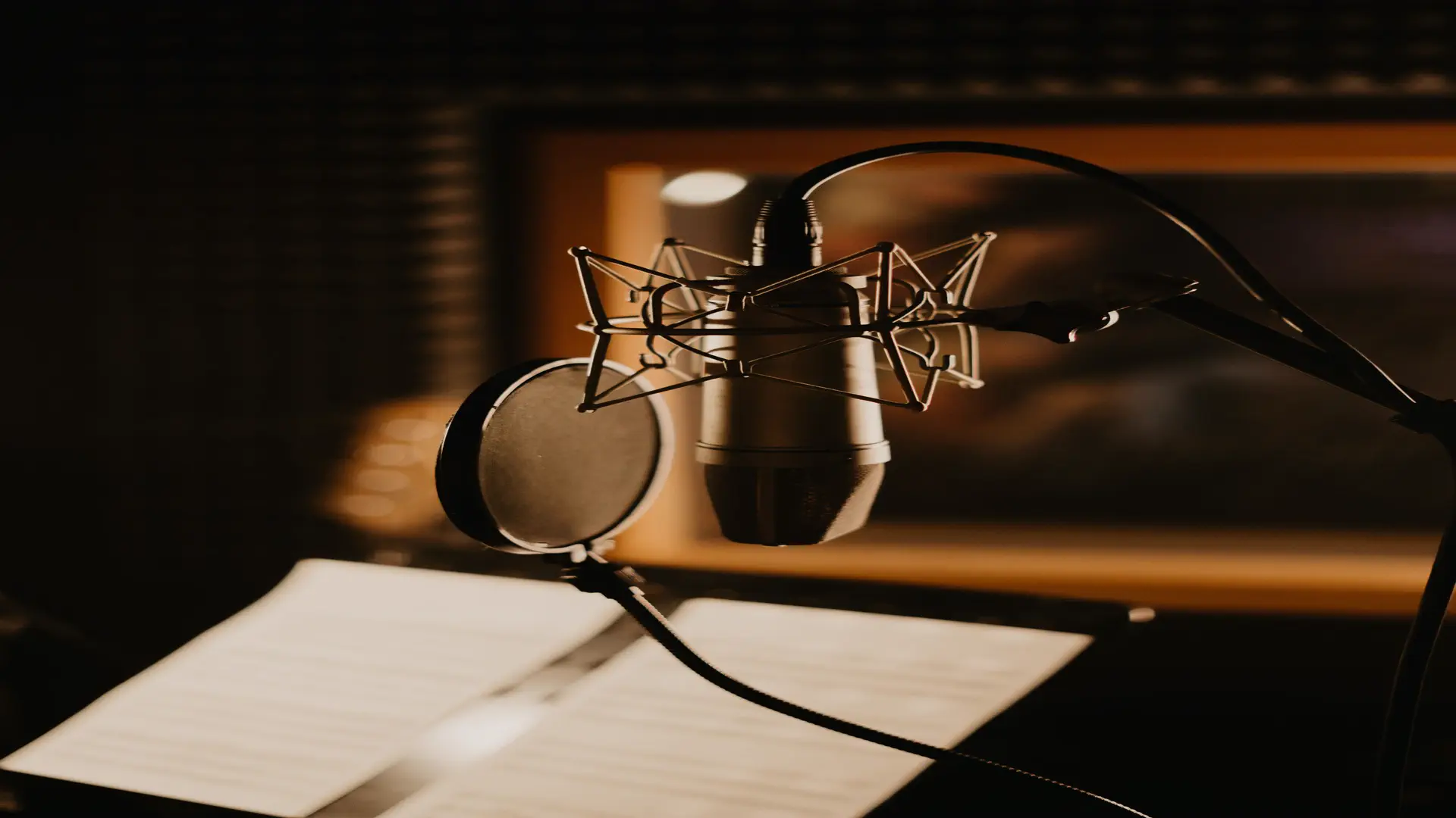 ElevenLabs Studio — real photo of a studio microphone with a pop filter over papers in a dim studio
