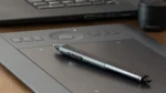 Midjourney prompts for beginners — real photo of a graphics tablet with a stylus pen beside a laptop