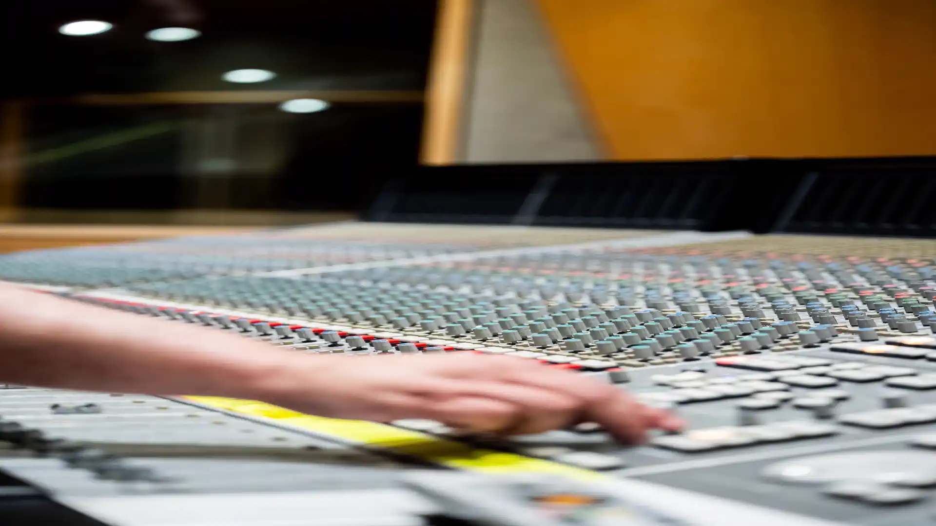Make a full song with Suno AI — real photo of a hand adjusting faders on a studio mixing console