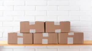 Oracle Fusion supply chain planning — real photo of stacked cardboard delivery boxes against a white brick wall