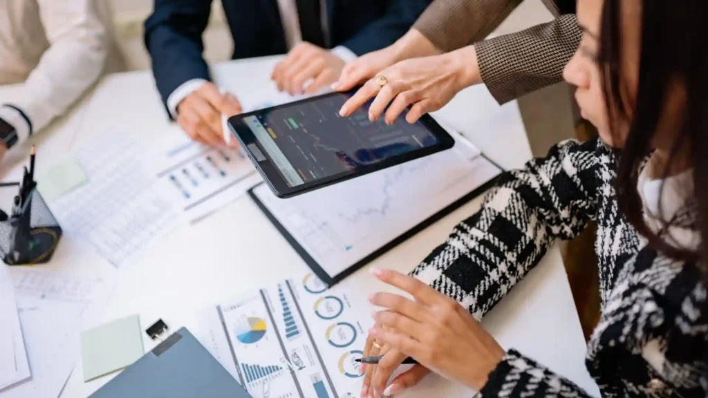 Strategic technology solutions — business professionals reviewing analytics charts on a tablet during a strategy meeting