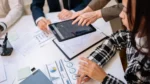 Strategic technology solutions — business professionals reviewing analytics charts on a tablet during a strategy meeting