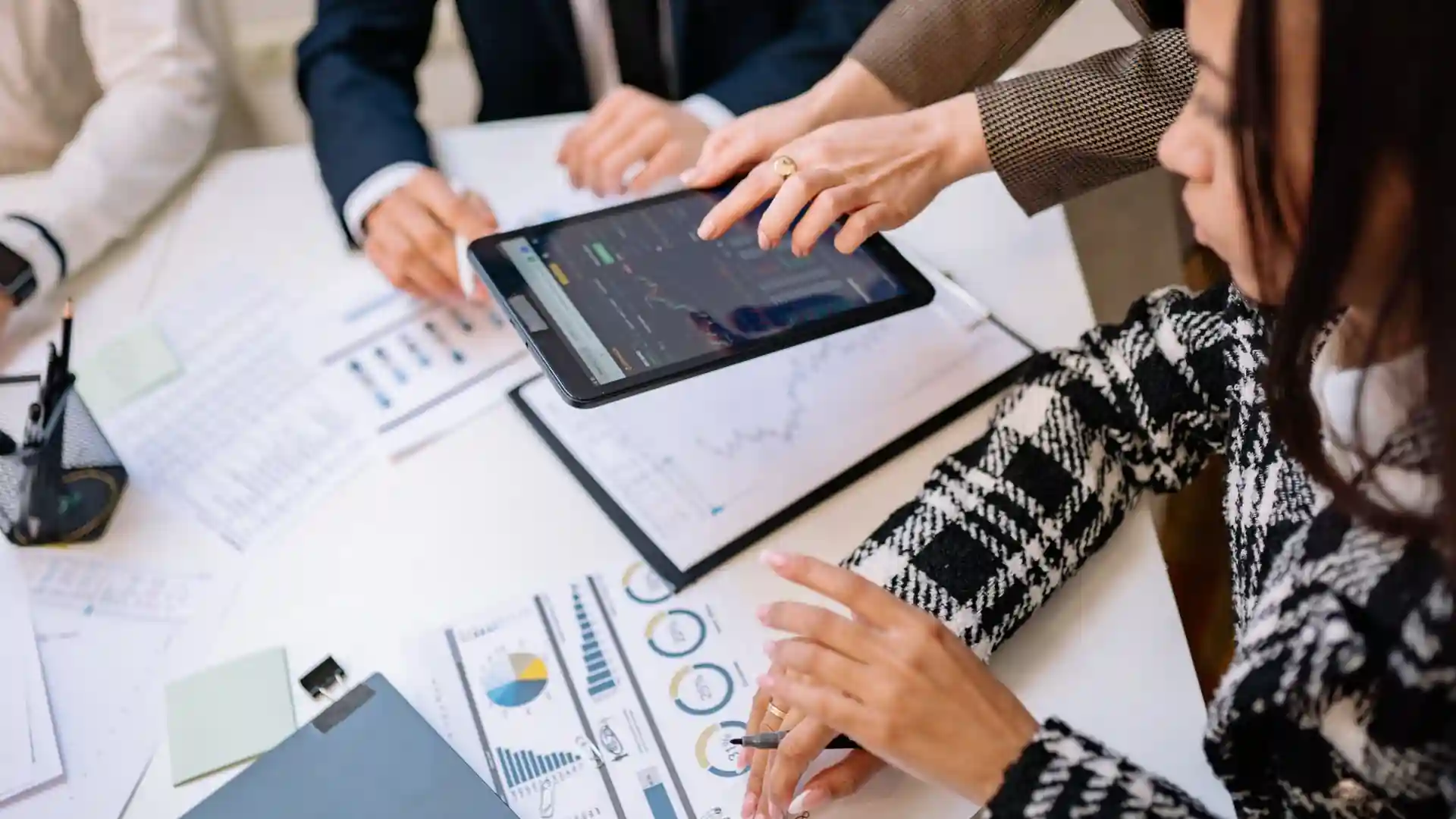Strategic technology solutions — business professionals reviewing analytics charts on a tablet during a strategy meeting