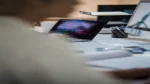 AI code documentation generator — real photo of a developer's desk with a laptop showing colorful code on a dark screen