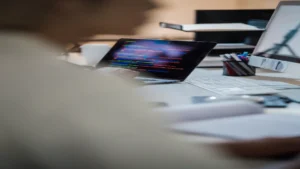 AI code documentation generator — real photo of a developer's desk with a laptop showing colorful code on a dark screen