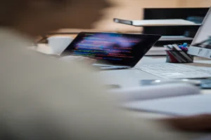 AI code documentation generator — real photo of a developer's desk with a laptop showing colorful code on a dark screen