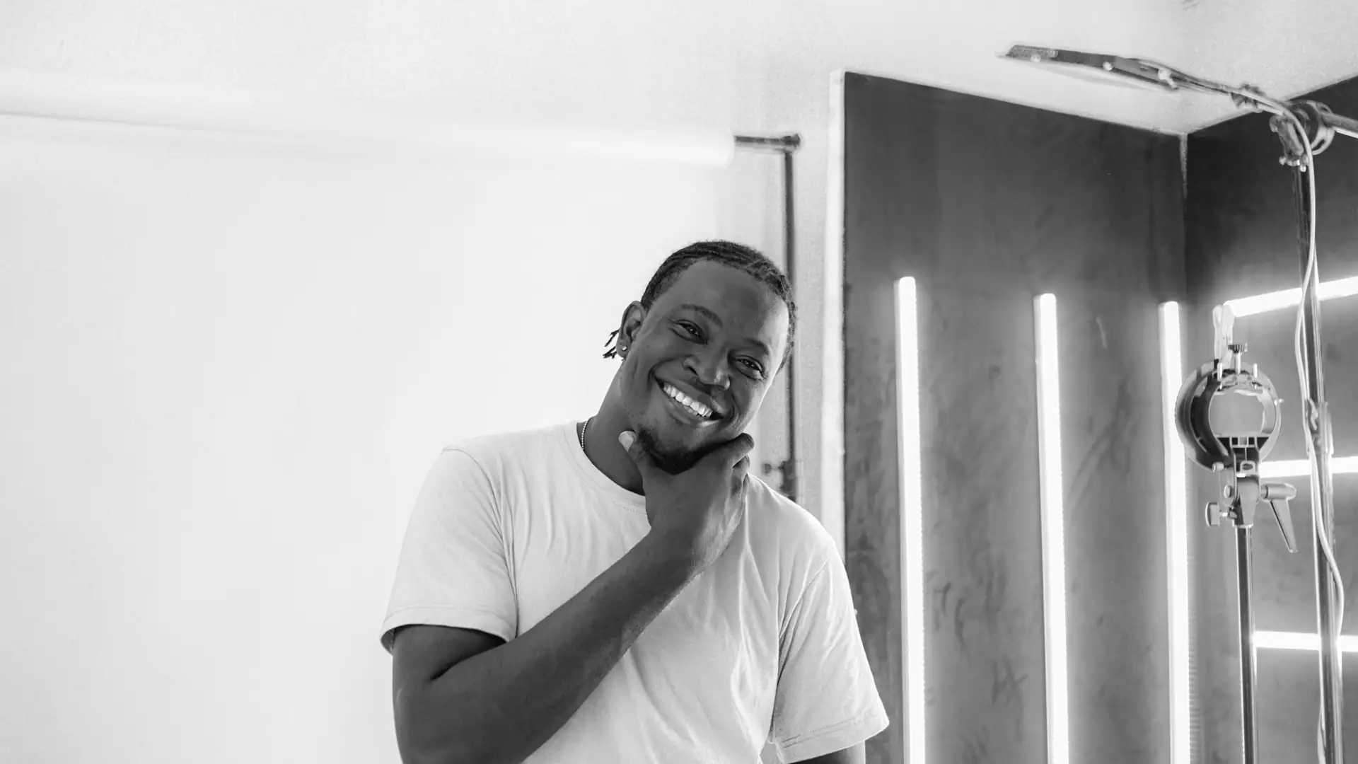 ai headshot generator free — a smiling man in a white t-shirt poses for a headshot portrait in a photo studio.