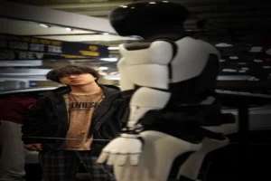 Humanoid robots shipped 2026 report — real photo of a white and black humanoid robot on display at an exhibition with a visitor beside it