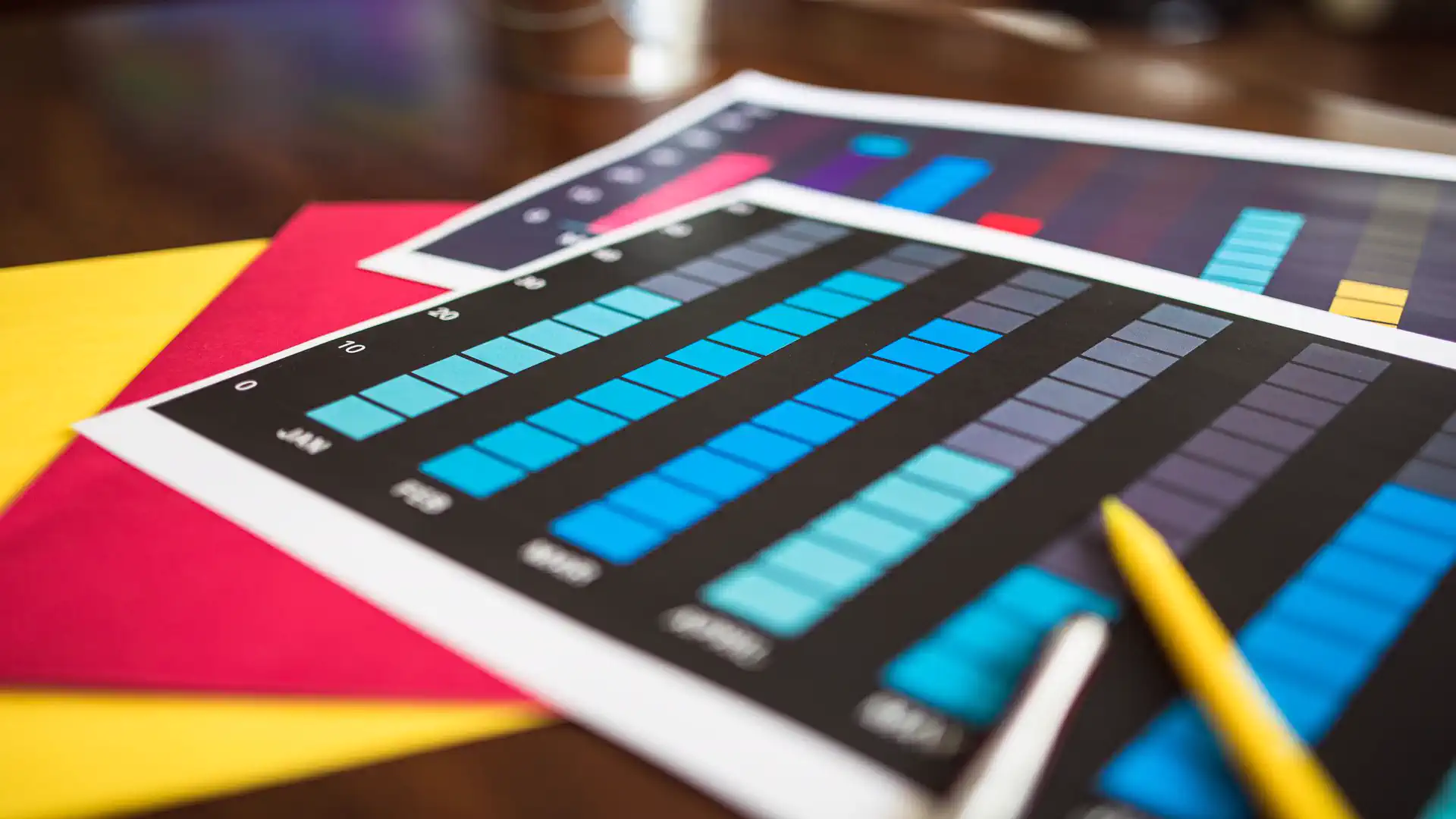 Free AI infographic generator online — real photo of printed colorful bar charts and infographics on a desk with a yellow pencil