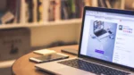 ai landing page builder — a laptop on a wooden desk displays a website design page beside a smartphone.