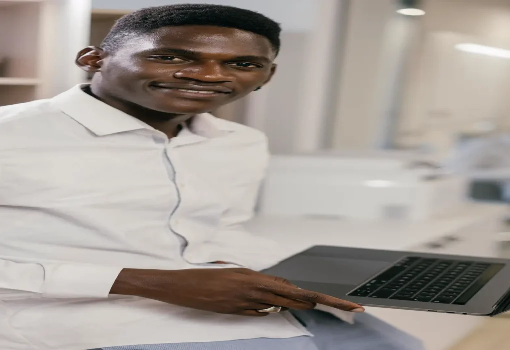 AI LinkedIn post generator — real photo of a smiling professional man in a white shirt holding a laptop in a bright office