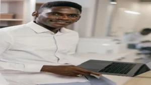 AI LinkedIn post generator — real photo of a smiling professional man in a white shirt holding a laptop in a bright office