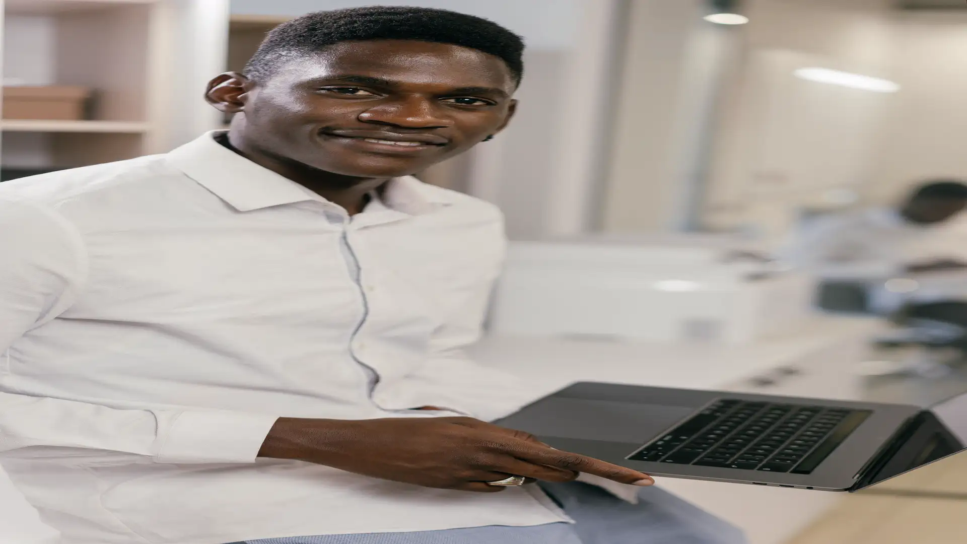 AI LinkedIn post generator — real photo of a smiling professional man in a white shirt holding a laptop in a bright office