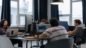 AI code generator free — real photo of software developers working on code at monitors in a bright office