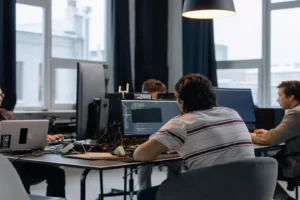 AI code generator free — real photo of software developers working on code at monitors in a bright office