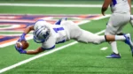 connections sports edition answers today — American football player in a white and blue uniform diving mid-air while holding the football during a game on a green field.