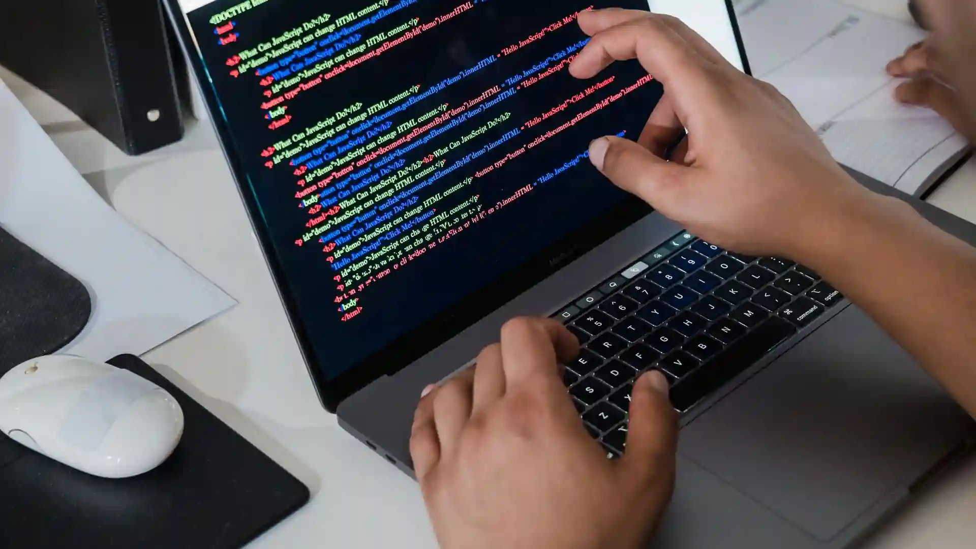 A person examining HTML and JavaScript code on a laptop screen, one finger pointing at a line.