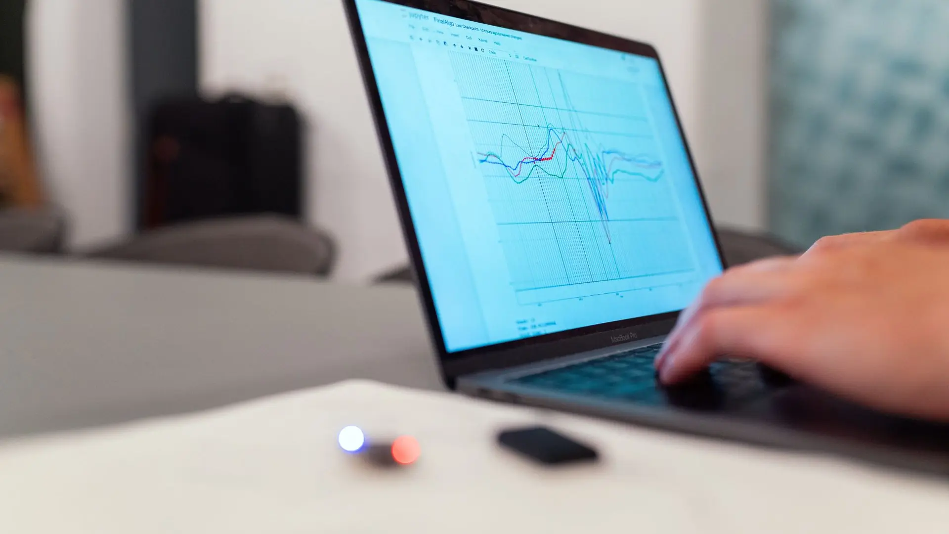 artificial intelligence versus machine learning — hand on a laptop keyboard with a multi-line data chart on screen showing how ML learns from data