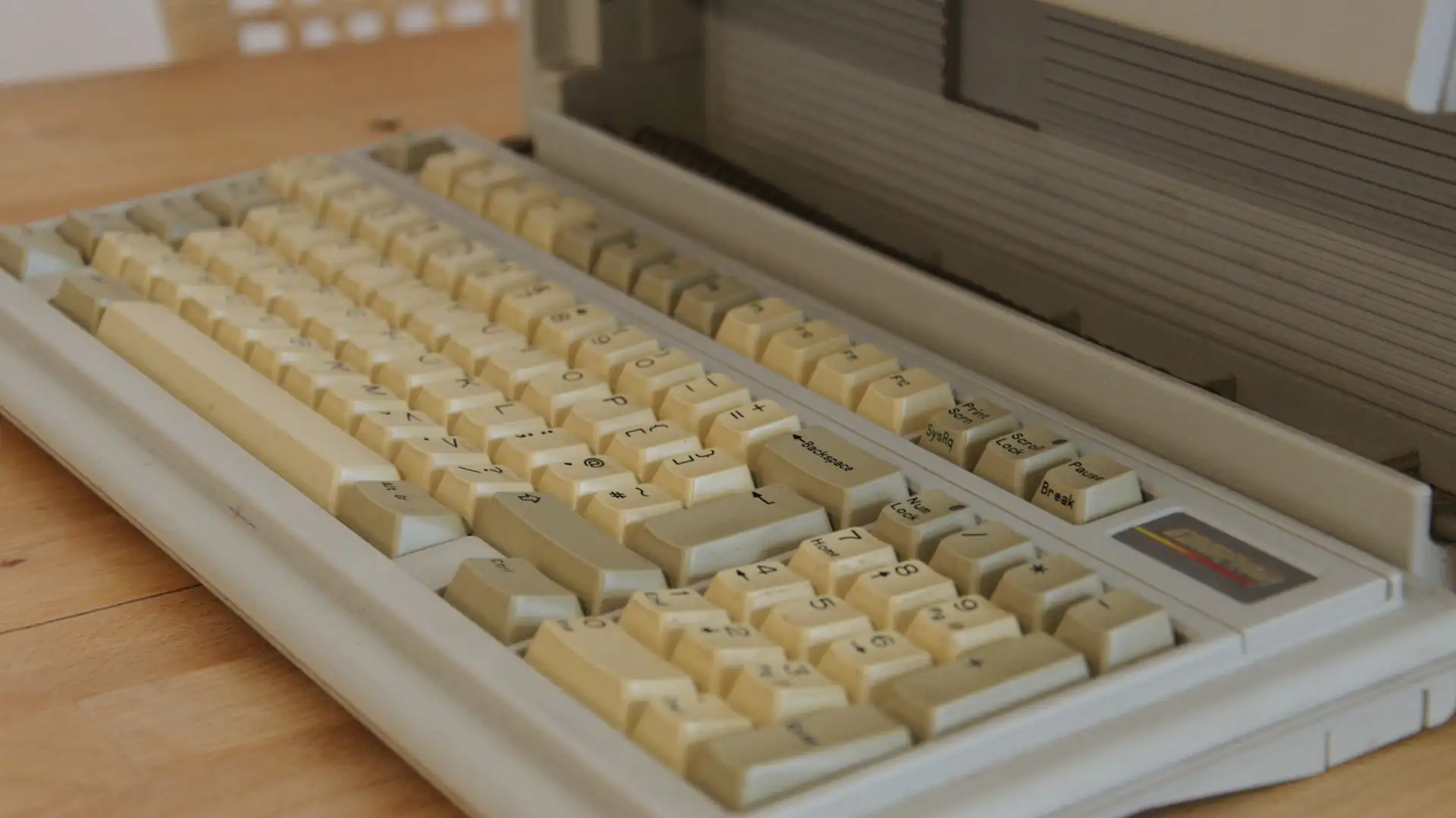 who created artificial intelligence — close-up of a yellowed vintage computer keyboard on a wooden desk