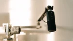 Clone your voice with AI for podcast intros — real photo of a black podcast microphone on a boom arm