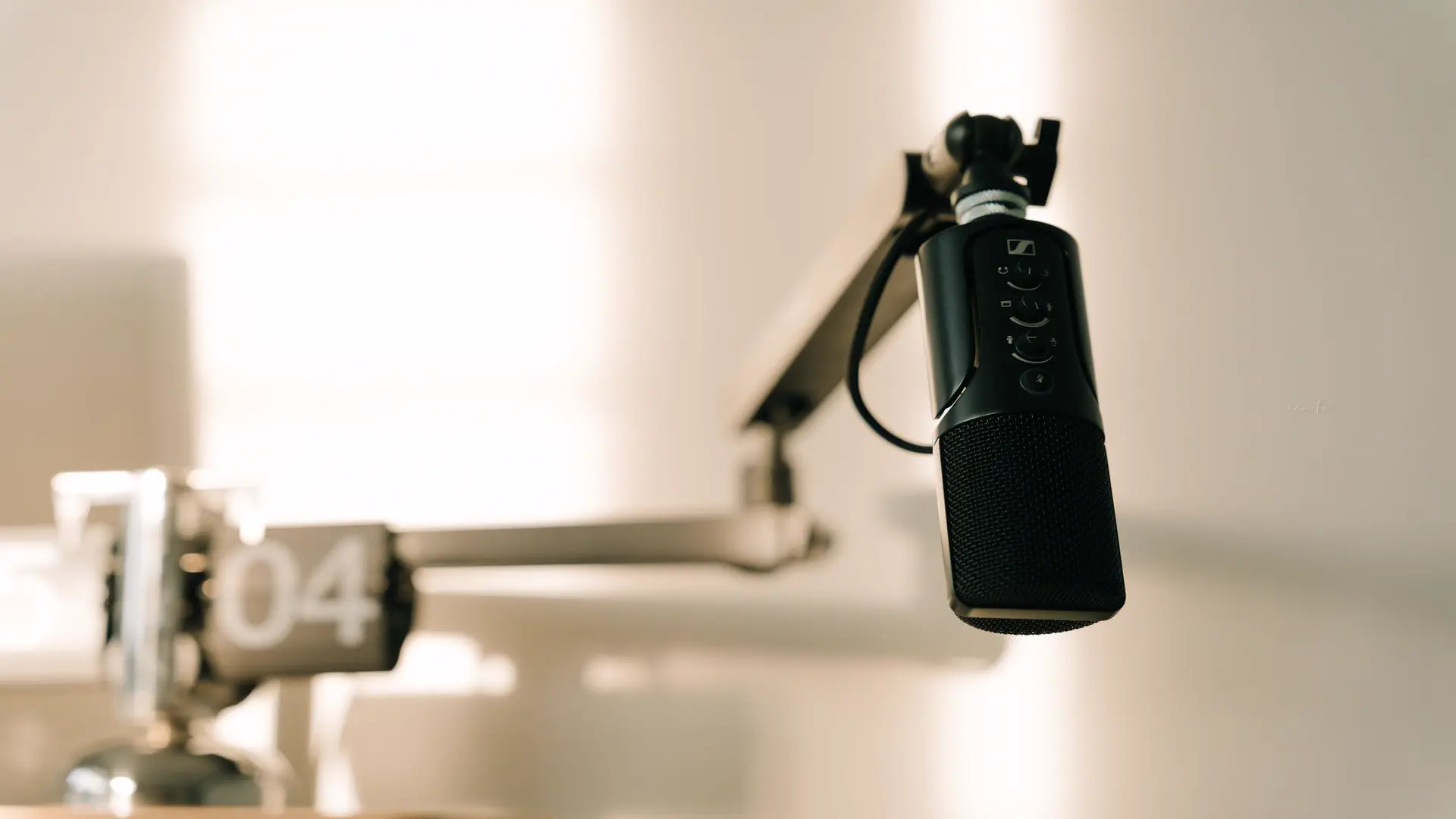 Clone your voice with AI for podcast intros — real photo of a black podcast microphone on a boom arm