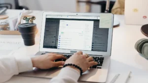 Automate cold email follow-ups with AI — real photo of a person typing on a laptop showing an email inbox app