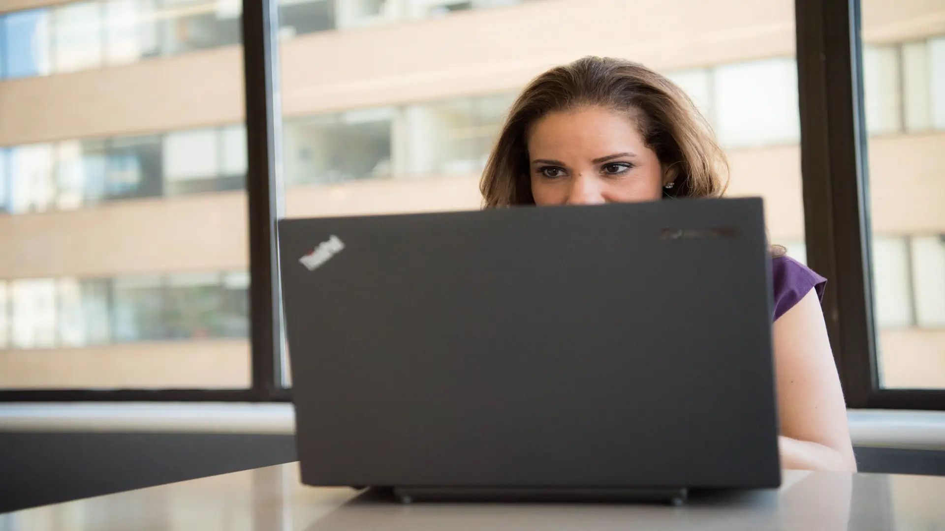 Build AI automation workflow without coding — real photo of a woman working on a laptop in a bright office