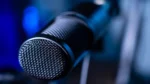 AI voice cloning for beginners — real photo of a close-up studio microphone with blue lighting