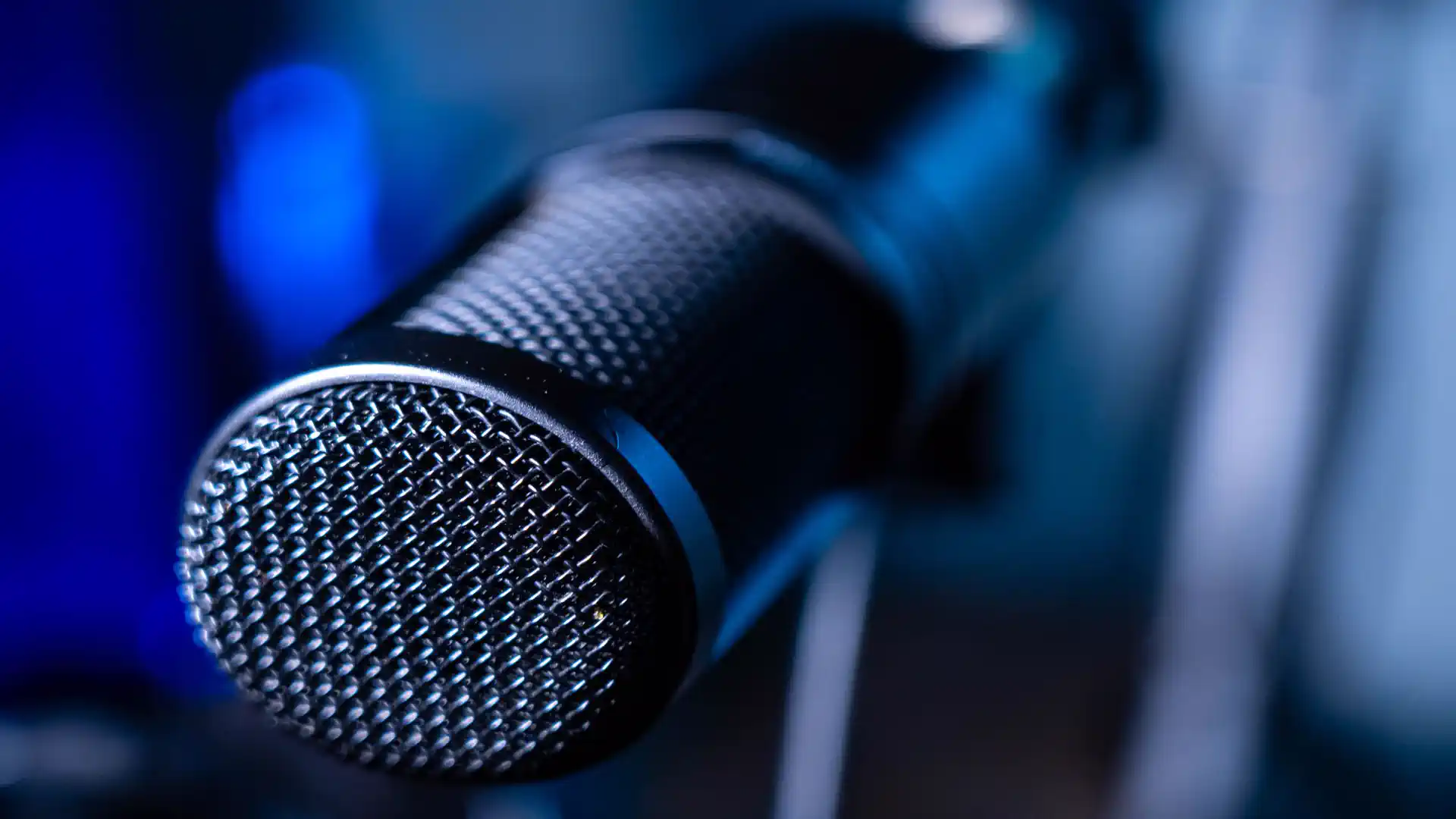 AI voice cloning for beginners — real photo of a close-up studio microphone with blue lighting