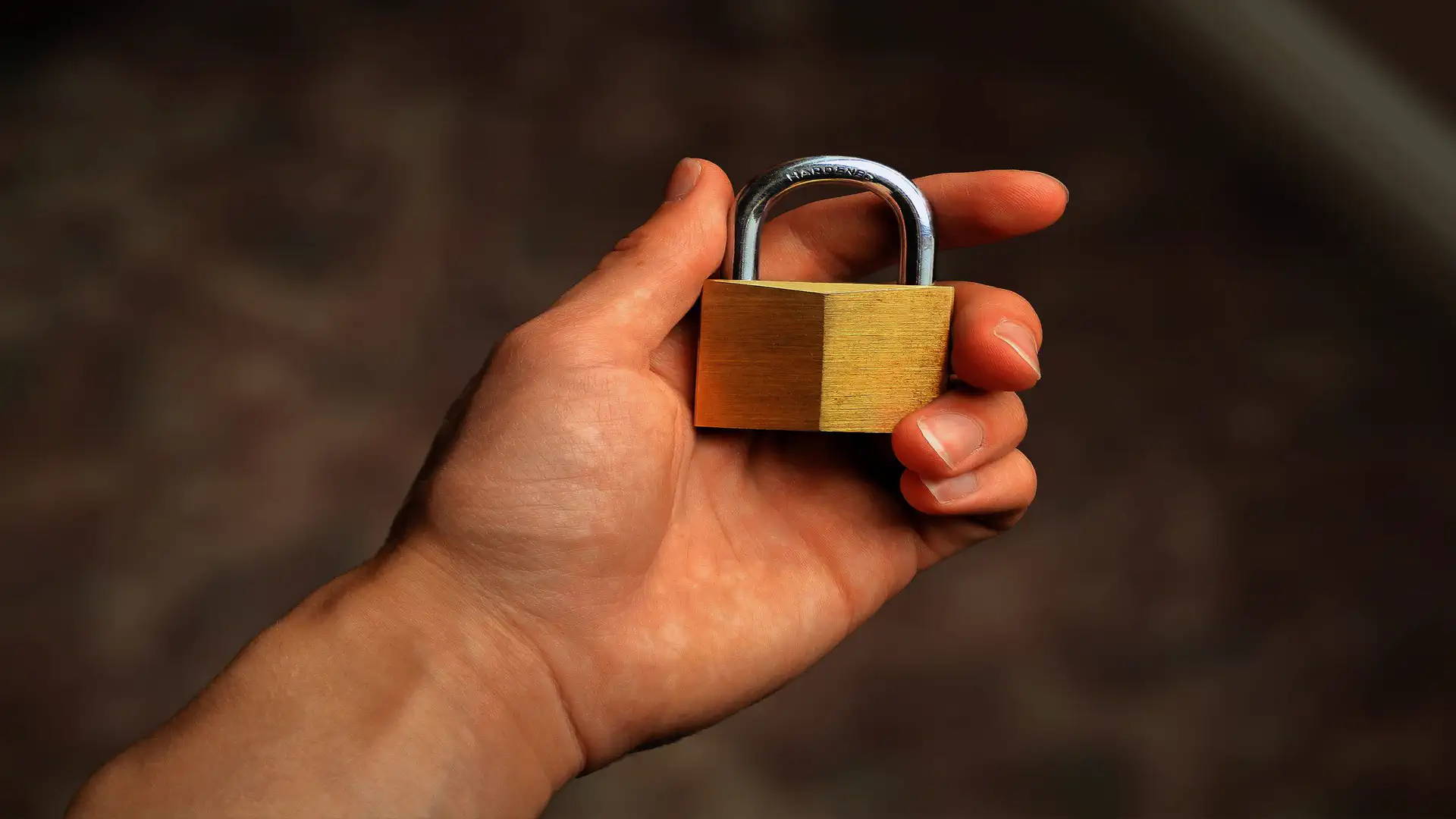 Cybersecurity AI automation — real photo of a hand holding a brass padlock